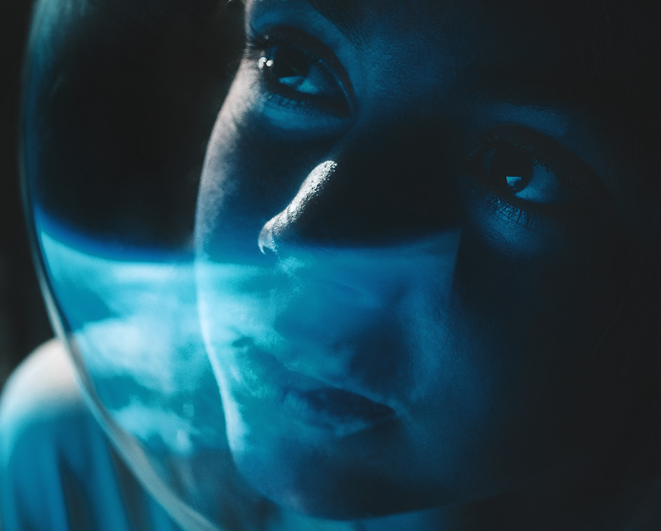 A young astronaut wearing a space helmet looks out to earth