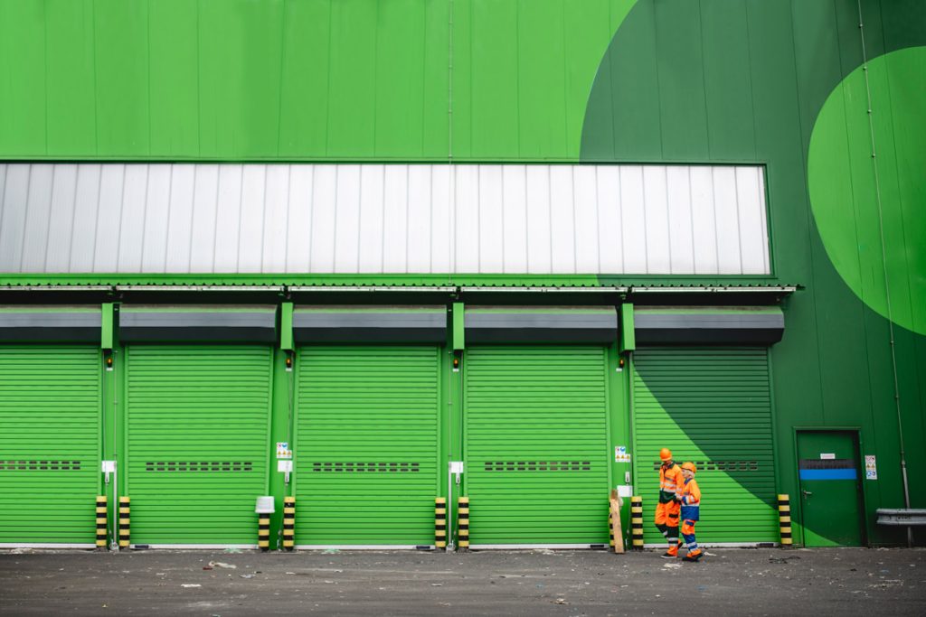 Factory workers walking past green factory doors