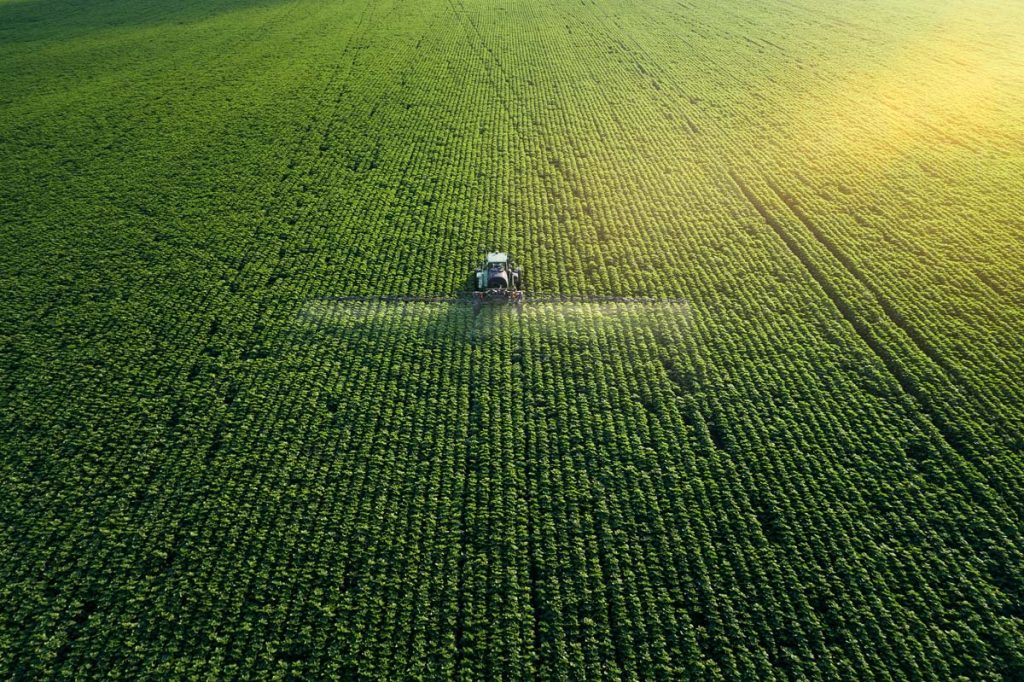 Farmer in machinery watering crops