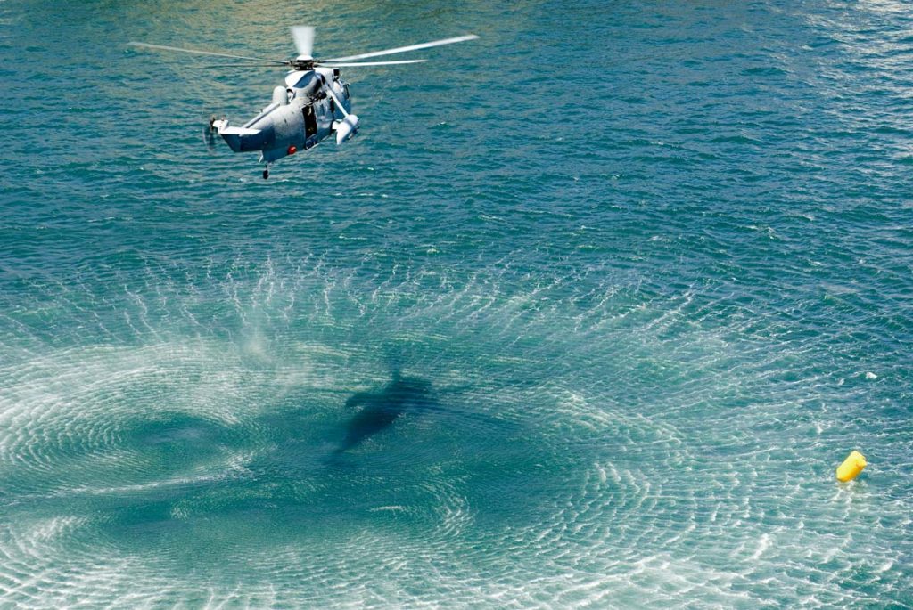 Navy rescue helicopter hovering above ocean