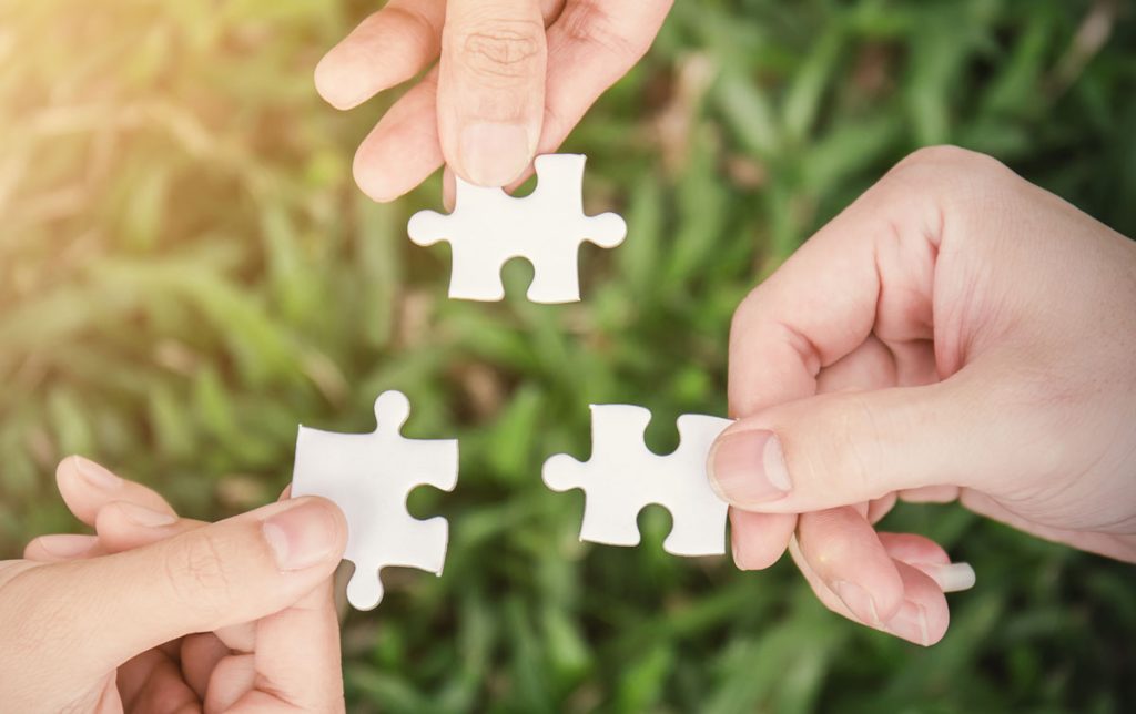 Hands holding three puzzle pieces