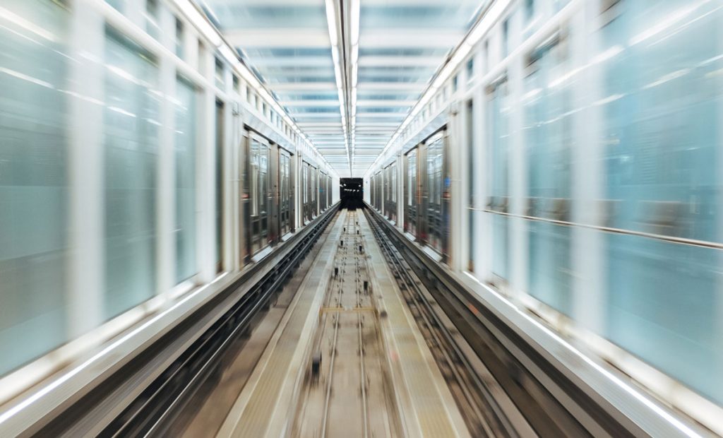 Train travelling fast through tunnel with glass walls